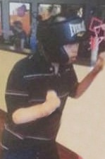 Photo of Brandon Strauss. He is a teenage boy with fair skin. He is wearing a striped polo shirt and his hair is hidden under his bulky helmet. He is leaning on something off to the right of the picture.