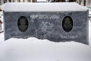 Gravestone of Sasha and Maxim Kordyukova. Their names are written in Cyrillic characters, and above each name is a dim black-and-white image of a young child. The bottom of the photograph is torn off so that the dates of birth and death cannot be seen.
