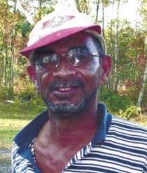 Photo of Dwight Ridley, a man with dark-brown skin and a salt-and-pepper beard, wearing a baseball cap and polo shirt, photographed outdoors.