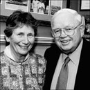 Black and white photo of Frank and Elizabeth Lackey. They have fair skin. She has dark hair and is wearing a sweater; he has light hair and is wearing a suit and glasses.