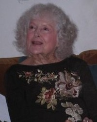 Photo of Irene McLean, an elderly woman with curly white hair and fair skin, wearing an embroidered sweater.