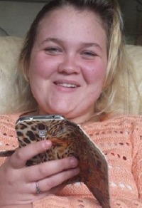 Photo of Jody Meyers. She has fair skin and blond hair with darker roots. She is holding a cell phone in a leopard-print cover, and wearing a silver ring and a peach sweater.