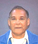 Photo of Manuel Reyes. He has tan skin and gray hair, and is wearing a blue sweater and white shirt.