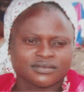 Photo of a dark-skinned African woman wearing a bright red top and a white calico head wrap.