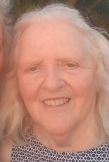 Photo of an older woman with white hair, brown eyes, and pale skin, smiling for the camera.