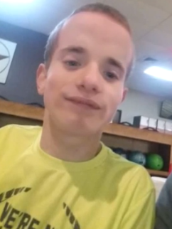 Photo of a young man with light skin and short, dark-blond hair, wearing a yellow shirt.