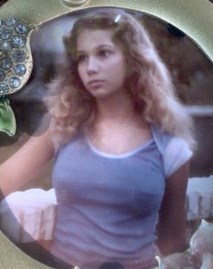 Photo of Lorraine Miranda, a young fair-skinned woman with long wavy hair, wearing a blue shirt, with a pensive expression on her face.