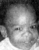 Grainy black-and-white photo of a baby with dark skin, dark eyes, short hair, and a wide, upturned nose.
