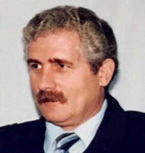 Photo of a middle-aged man with salt-and-pepper hair and mustache, wearing a suit.