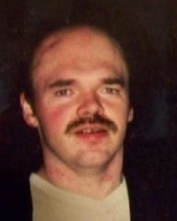Photo of a balding man with light skin and a mustache.