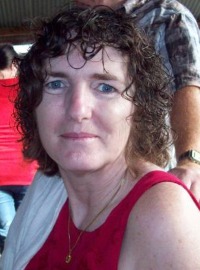 Photo of Elizabeth Knowles. She has pale skin, chin-length curly brown hair, and blue eyes. She is smiling slightly. She is wearing a pink sleeveless shirt and a silver necklace.