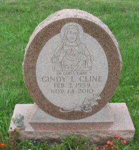 Cynthia Cline's gravestone, an oval stone carved with an image of Jesus and the words "In God's Care".
