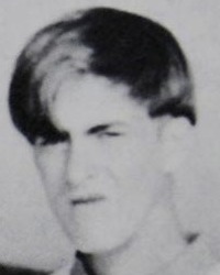 Blurry black and white yearbook photo of a young man with his hair falling over his eyes; he looks like the photo was taken before he got the chance to smile.