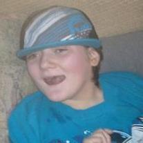 Photo of Camaron Larson, a child wearing a turquoise shirt and turqoise baseball cap. He has fair skin and light brown hair and is smiling.