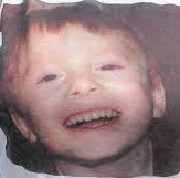 Photo of a young boy, printed on cloth. The boy has wispy auburn hair and is smiling.