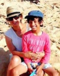 Photo of Liam Milne and his mother Susana. Liam is a light-brown-skinned boy with curly black hair, wearing a baseball cap and pink shirt. His mother is a woman with brown hair and pale skin, wearing sunglasses and a straw hat. She has her arms around Liam.