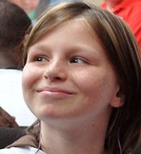 Photo of Zahra Baker, a girl with straight brown hair and freckles, smiling at something to the left of the viewer.