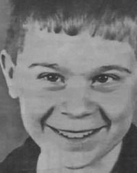 Black and white photo of a smiling boy with light skin and short hair.