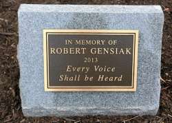 Granite gravestone with a brass plaque reading, "In memory of Robert Gensiak, 2013. Every voice shall be heard."