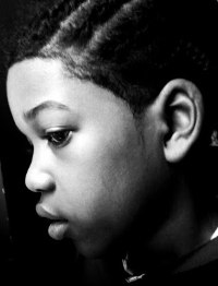 Black and white side-profile photo of Kenneth Holmes, an African-American boy with his hair in cornrows.