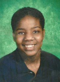 Photo of Leosha Barnett, a young woman with brown skin and black hair pulled back from her face; she is smiling for the camera.