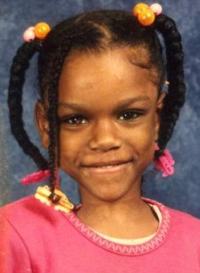 Photo of Markea Blakely-Berry, a girl of about eight years old, with her black hair in beaded pigtails. She has brown skin, and is wearing a pink sweater; she is smiling, showing baby teeth.