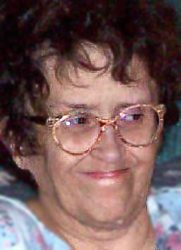 Photo of Criste Reimer, a middle-aged woman wearing glasses. She has pale skin and curly brown hair, cut short. She is smiling with her lips pressed together.