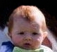 Photo of a small, pale-skinned infant with wispy dark-red hair.