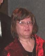 Photo of Mary Swierzewski, a middle-aged woman with fair skin and chin-length blond hair, wearing a red blouse.