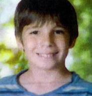 Photo: A boy with brown hair and light-brown skin, smiling; he is wearing a blue striped shirt.