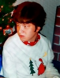 Photo of Courtney Liltz, a young woman with short, curly brown hair and fair skin. She wears a Christmas sweater. 