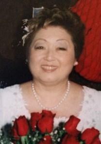 Photo of Margaret Yamaguchi, a middle-aged Asian woman wearing a white dress and holding a bouquet of red roses.