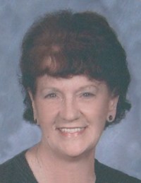Portrait photo of Cathy Evans. She is a middle-aged woman with permed dark-brown hair and pale skin.