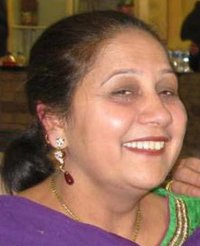 Photo of Jagtar Gill, a middle-aged woman with light brown skin and dark brown hair, wearing make-up, earrings, and a brightly colored green and purple top.