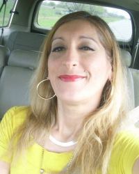 Photo of Noemi Villarreal. She is a woman with pale skin and straight blond hair; she is wearing a yellow shirt, jewelry, and make-up.