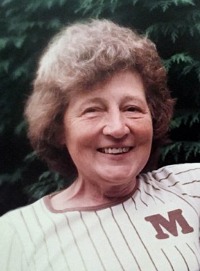 Photo of Margaret Meyer, an elderly woman with curly gray hair and fair skin. She is wearing a sports jersey with the monograph "M" on it.