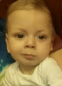 Photo of Kobe Shaw, a fair-skinned baby wearing a white onesie; he has brown eyes and wispy light-brown hair.