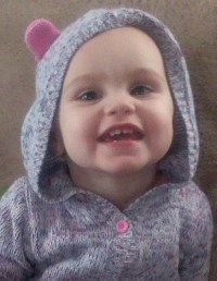Photo of Maddox Lawrence, a baby with fair skin. She is wearing a gray knit jacket with a hood decorated with pink animal ears.