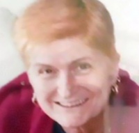 Photo of Laraine Rayner. She is a middle-aged woman with short strawberry-blonde hair. She is wearing hoop earrings and a red sweater.