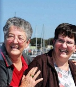 Photo of Janice and Robyn Frescura. Janice is an older woman with fair skin and gray hair; Robyn is a middle-aged woman with brown hair and fair skin. Both women are wearing glasses, shirts and jackets.