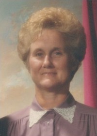 Portrait photo of Phyllis Mansfield, a middle-aged woman with short, permed blond hair, blue eyes, and fair skin. She wears a pink blouse with white collar.