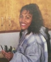 Photo of Sonia Riang, an African-American woman with medium-brown skin and curly black hair. She is wearing a flannel jacket and smiling.