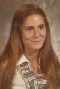 Portrait photo of Erin Leinweber, a young woman with long light-brown hair, fair skin, and brown eyes. She is wearing a blouse and is smiling with her lips shut.