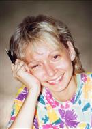 Photo of Jocelyne Lizotte, a middle-aged woman with graying light-brown hair cut to chin length. She is leaning her head against her hand, smiling, and wearing a flower-print shirt.
