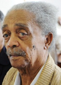 Photo of Peter Abrahams, an elderly African man with medium-brown skin and white hair and mustache.