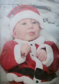 Photo of Cameron Hoopengarner, a baby with fair skin, wearing a Santa Claus costume.