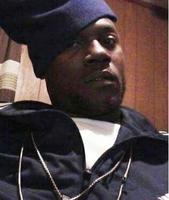 Photo of Troymaine Johnson, an African-American man wearing a navy windbreaker and blue knit cap.