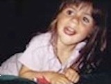 Photo of Logan Marr, a small girl with fair skin and light brown hair, wearing a pink T-shirt; she is licking her lower lip and looking off to the side.