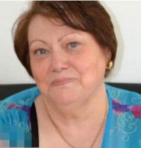 Photo of Leah Cohen, a middle-aged woman with fair skin and short, straight brown hair. She is wearing a turquoise blouse and small gold hoop earrings.
