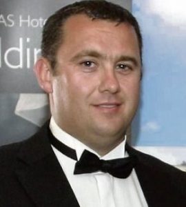 Photo of Jason Corbett, a young man wearing a tuxedo with a bow tie. He has fair skin, dark brown hair, and a receding hairline.